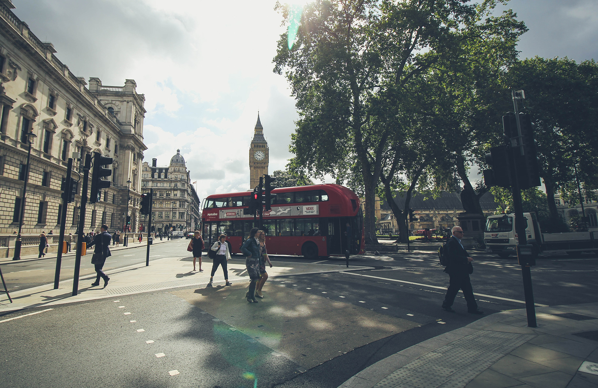 a doubledecker bus driving through the streets of london and big ben in the background