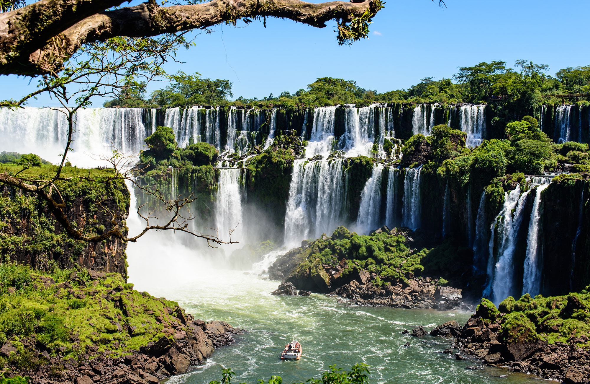 Iguazu Falls on the border between Argentina and Brazil, with a boat in the water in front of the waterfalls