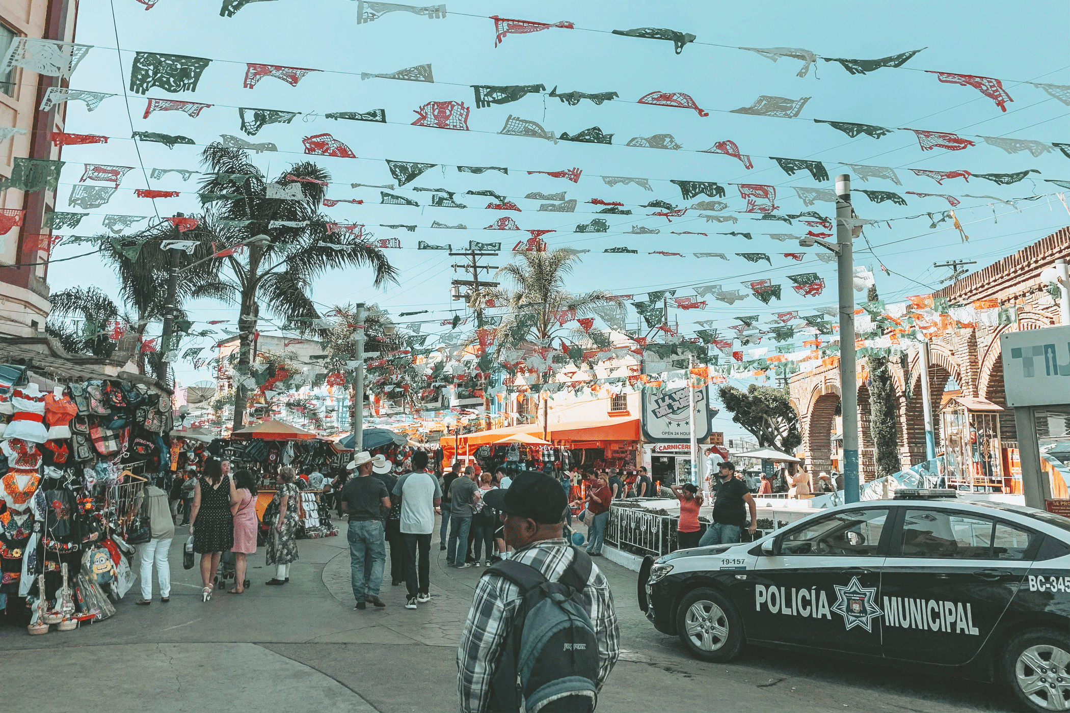 Busy street with a lot of people and a police car in Baja California in Mexico