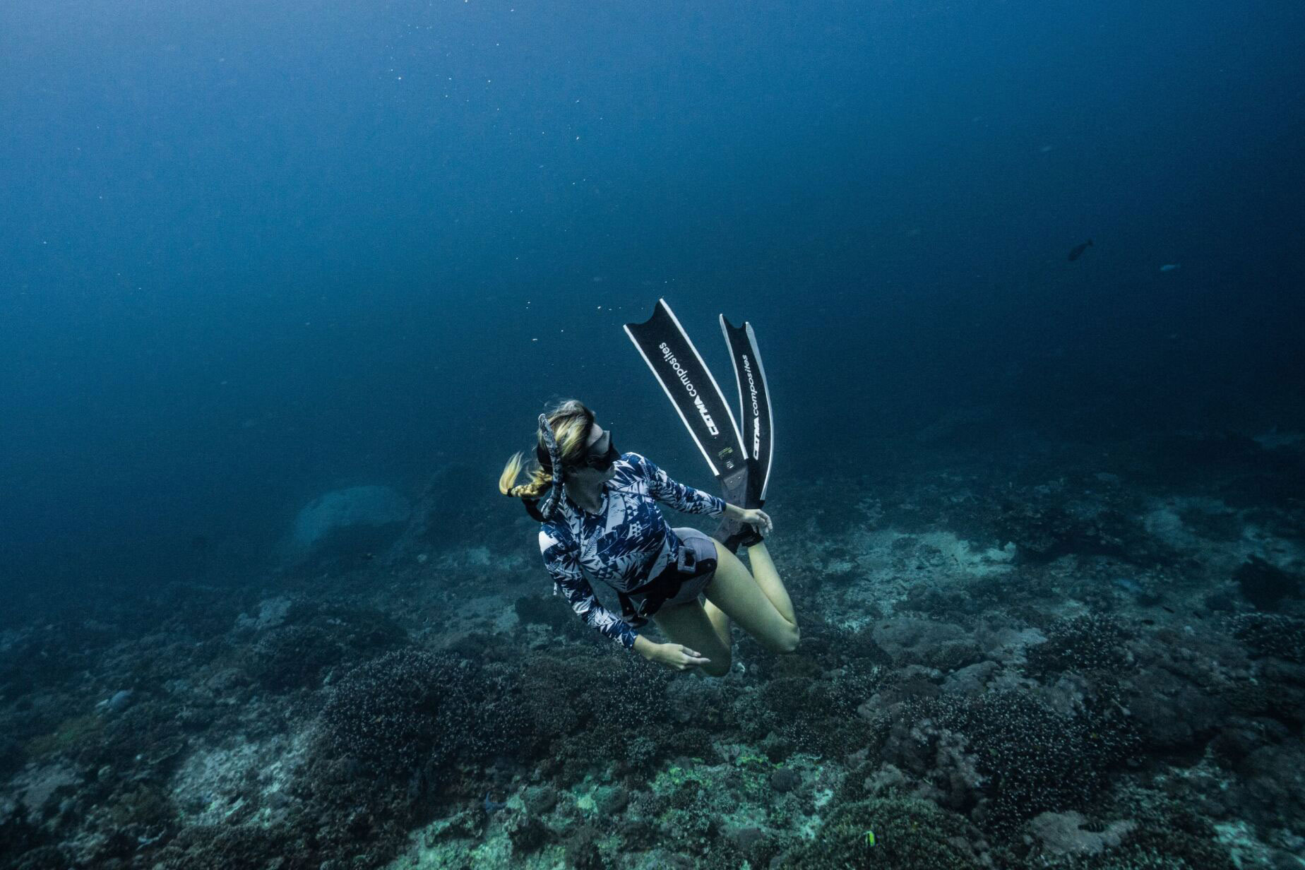 Girl with blonde hair freediving in the ocean around Bali in Indonesia