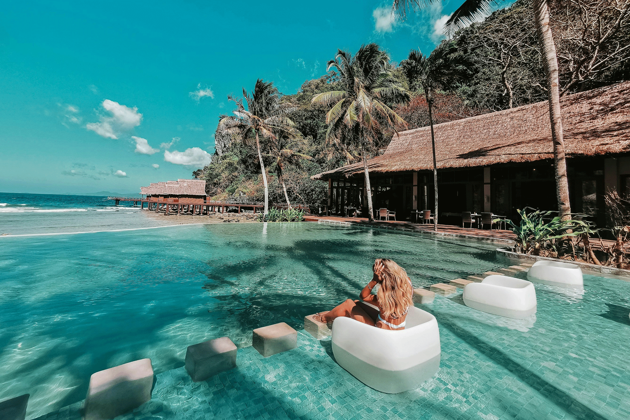 Girl sitting in the water at a beach hotel in Palawan in the Philippines