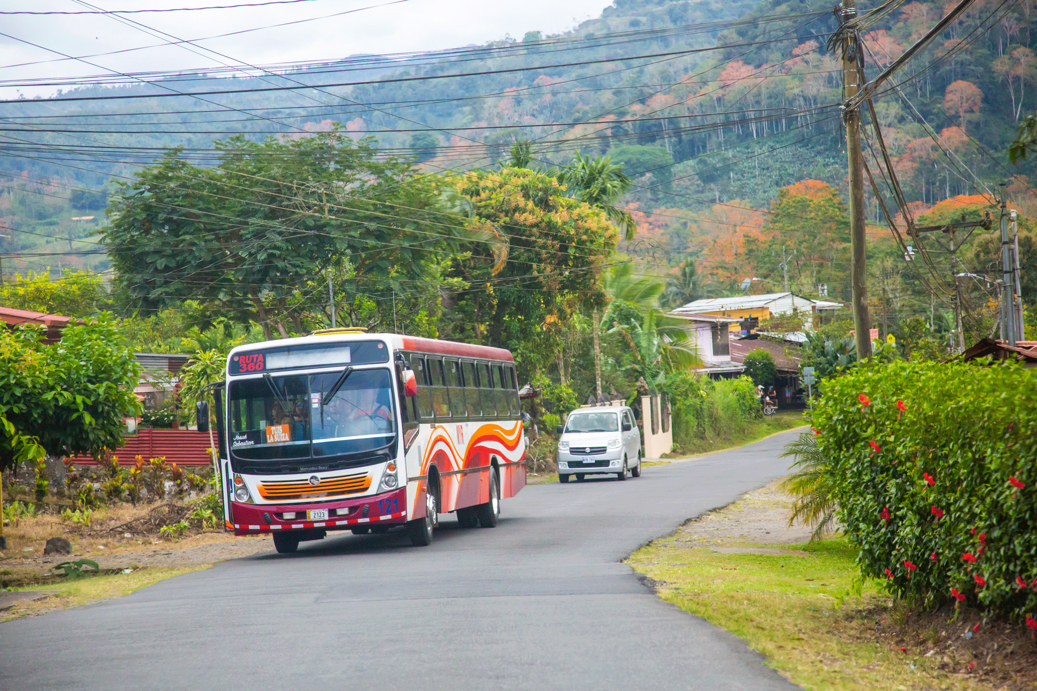 Red and white bus driving on a countryside road in Costa Rica