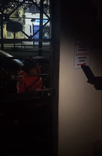 Thea stuck behind the electric gate of a hotel in Quito, with the Taxi driver trying to open the lock