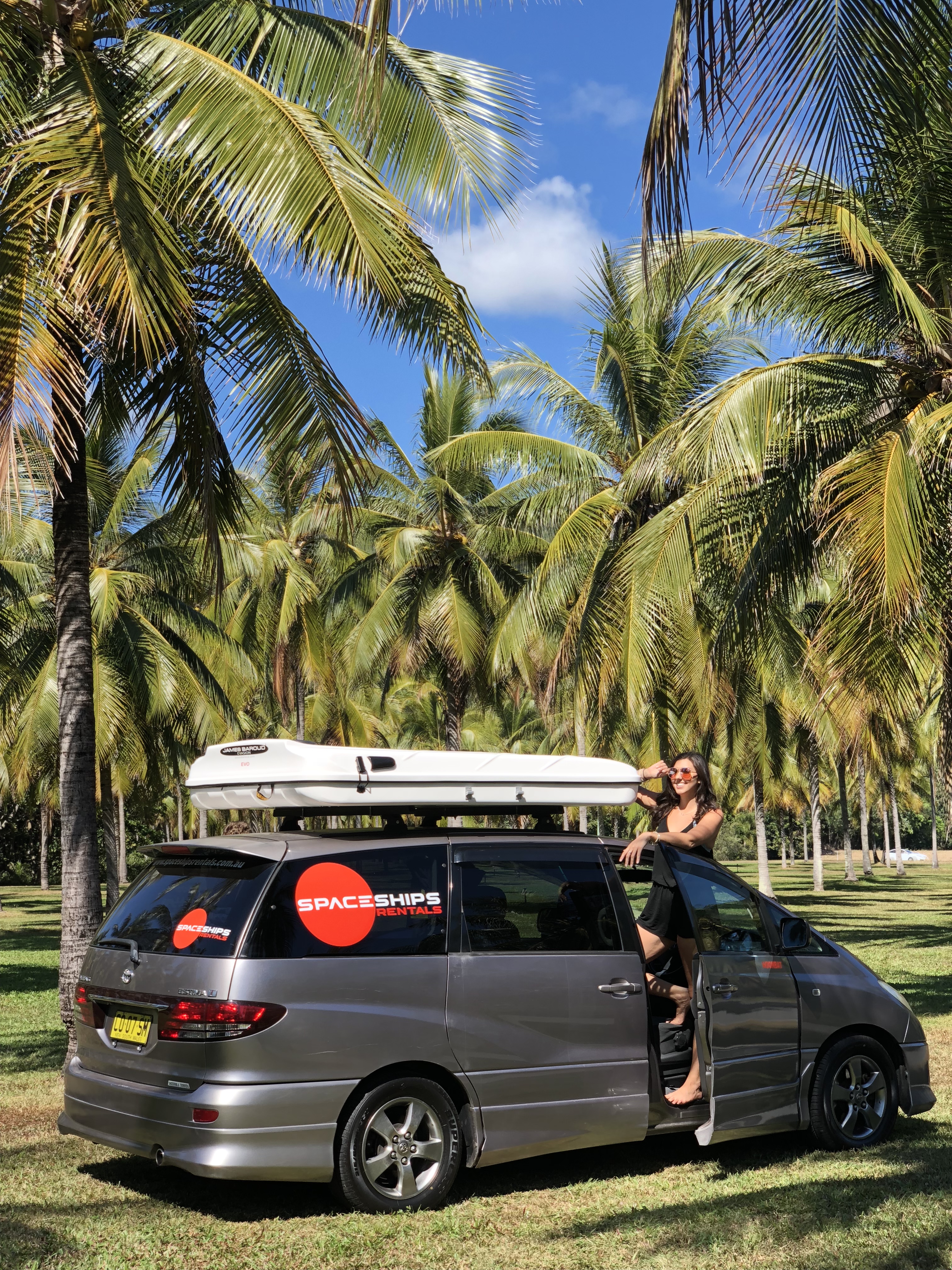 Woman standing in the open door of a grey Spaceships 4-berth campervan. 