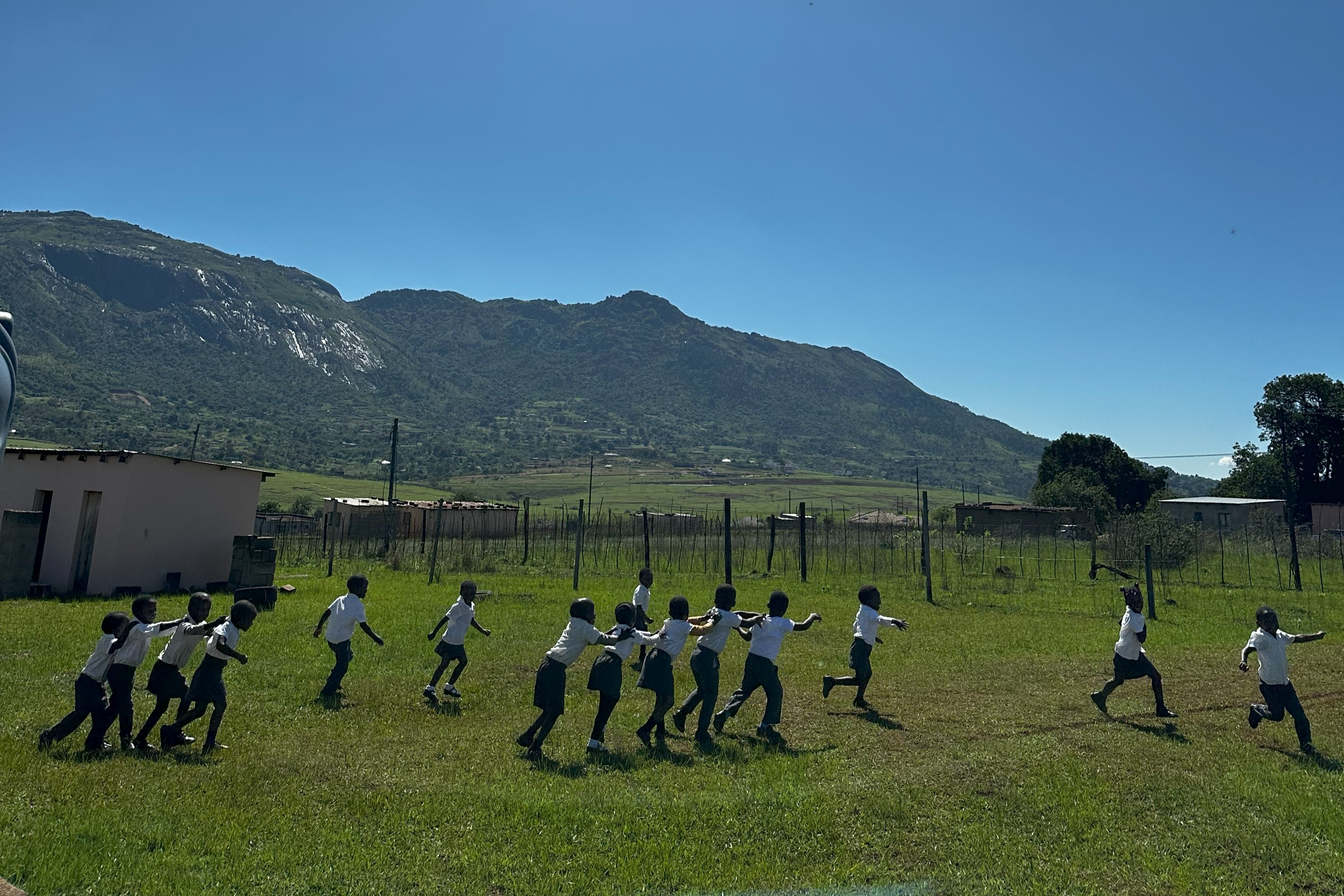 Guy standing in a field in Eswatini, looking at the mountainous view