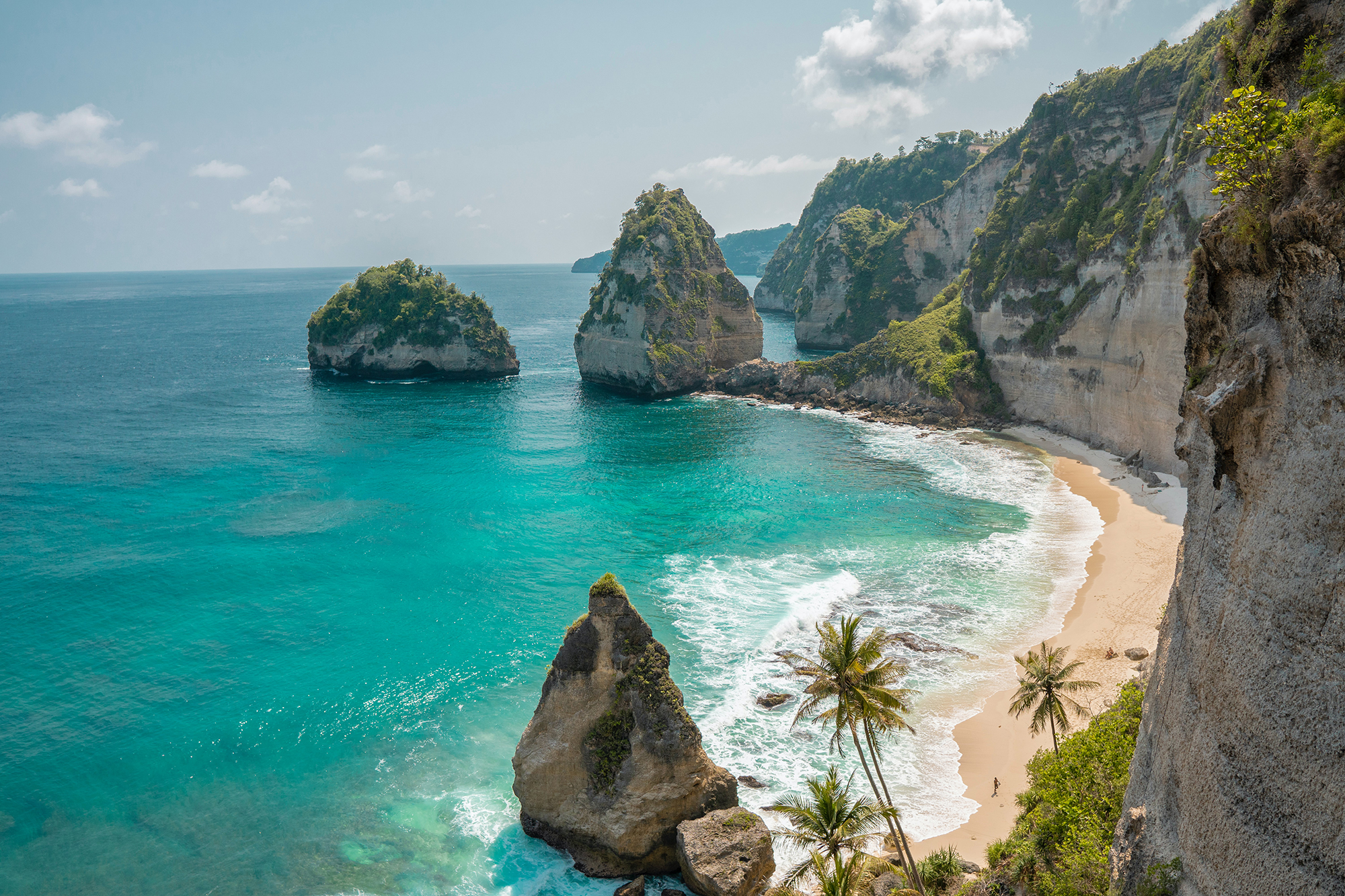 The famous limestone cliffs with an almost empty beach and green vegetation on Nusa Penida island in Indonesia