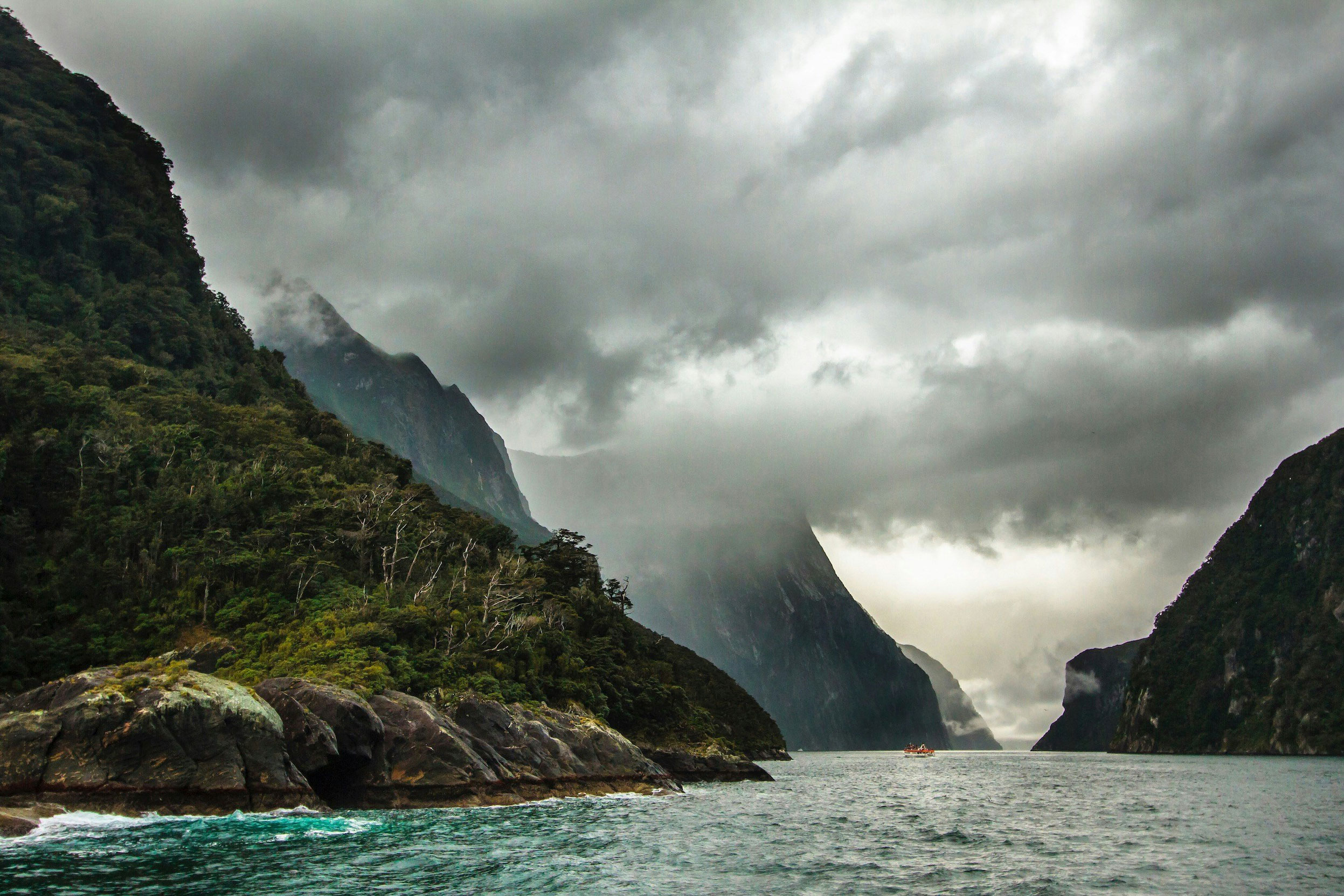 Heavy clouds hanging over the fjords of Millford Sound, with a boat in the distance